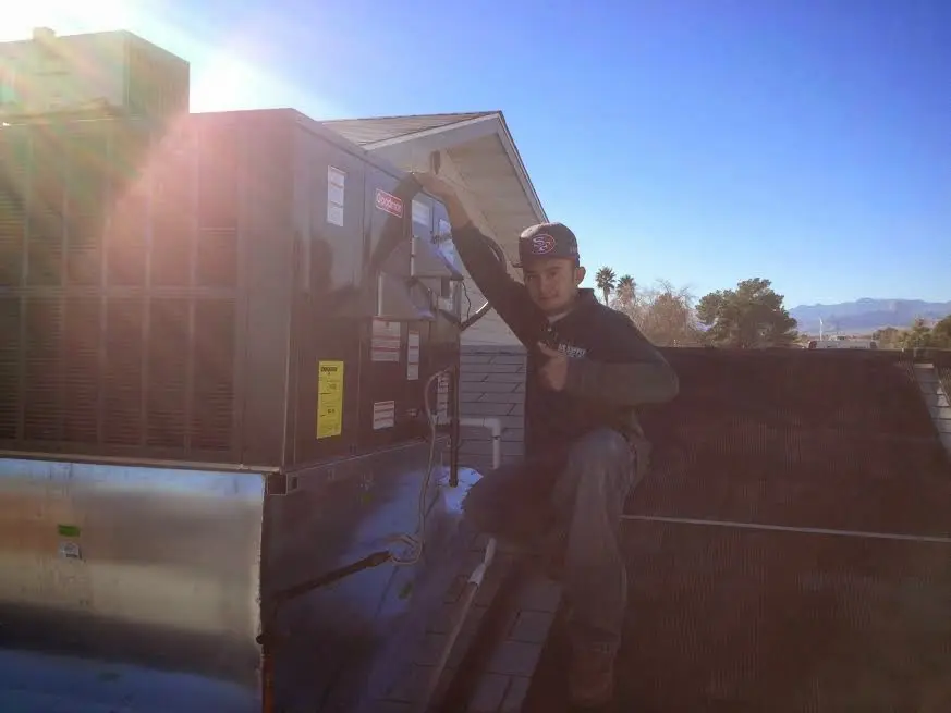 HVAC technician performing AC Tune-Up on a rooftop unit in Fall River