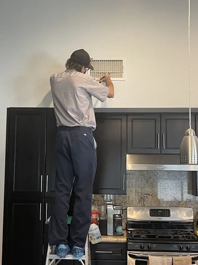 Technician inspecting an air vent during HVAC service in Fall River